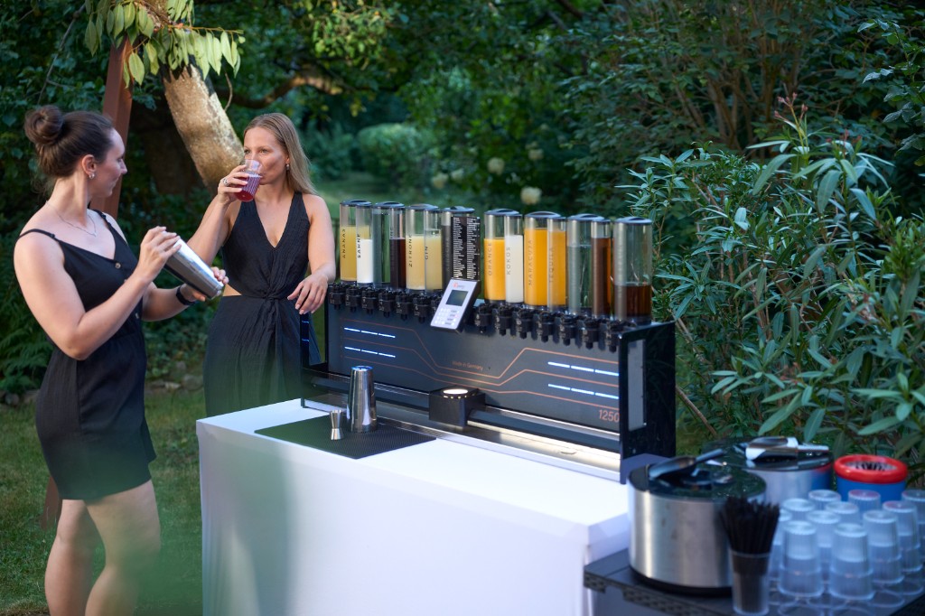 Gäste zapfen Cocktails aus der Maschine in Gläser