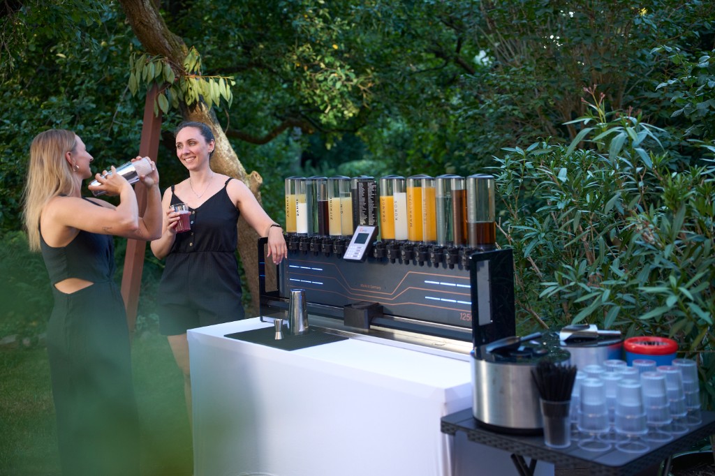 Zwei Gäste bedienen die Cocktailmaschine an der Bar